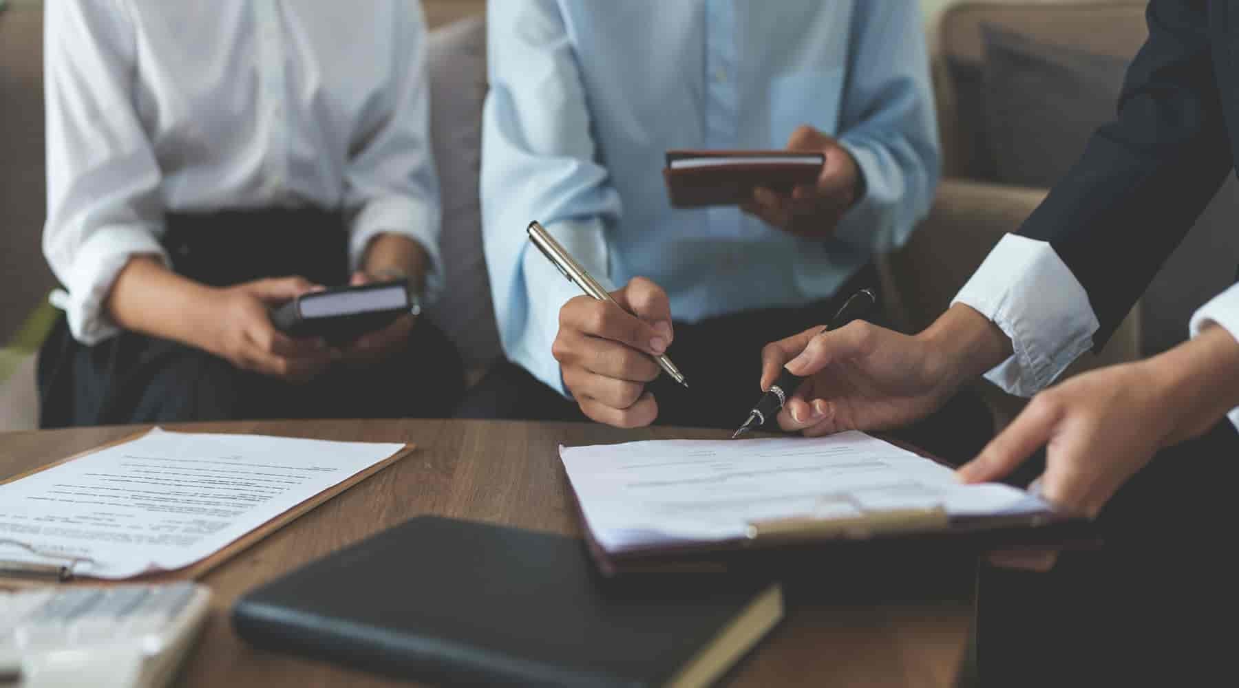 Beratungsgespräch zu Immobilienfinanzierung und Versicherungsunterlagen am Schreibtisch