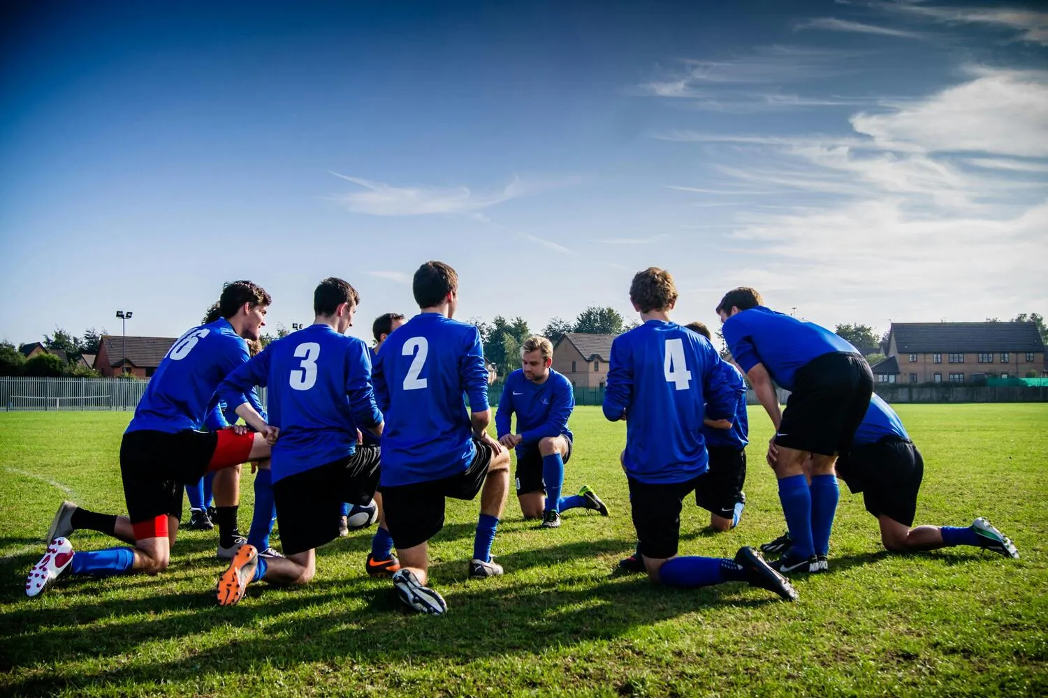 Amateur-Fußballmannschaft kniet in einer Besprechung auf dem Spielfeld